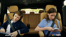 a boy and a girl are in the back seat of a car with nbc written on the bottom