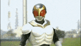 a man in a masked rider costume is standing in a field looking at the camera .