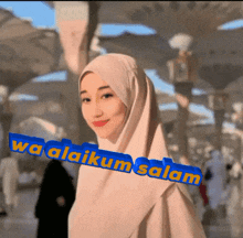 a woman wearing a hijab stands in front of a sign that says " wa alaikum salam "