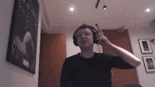 a man wearing headphones is standing in front of a wall with a picture on it that says ' twins '