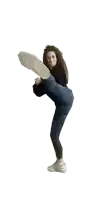 a woman in a black sweater and blue jeans is kicking her leg in the air