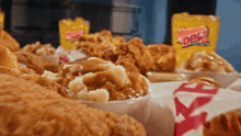 a bowl of mashed potatoes sits on a table next to fried chicken and a bag of dew