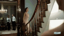 a woman in a white dress is walking down a set of stairs with a tv land logo in the corner