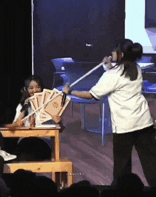 two women are playing a game on a stage and one of them is holding a sword