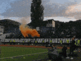 a soccer field with smoke coming out of the stands and a banner that says ' sporting club ' on it
