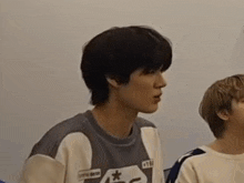 a boy with short hair is making a funny face while another boy looks on .