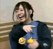 a woman is laughing while pointing at a smiley face .