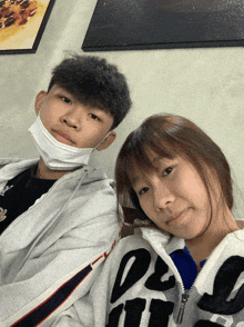 a boy wearing a mask and a girl wearing a jacket with the letter l on it are posing for a picture