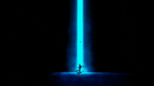 a man is standing in front of a blue light and a blue background .