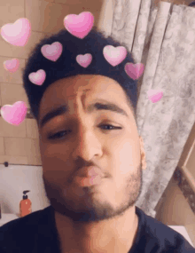 a man with a beard is making a funny face with pink hearts on his head