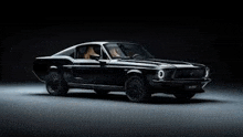 a black mustang is parked in a dark room on a gray surface .