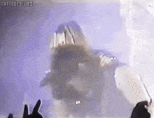 a man is standing on a stage in front of a crowd while wearing a gas mask .