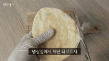 a person wearing white gloves is cutting a piece of dough