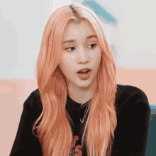 a woman with long pink hair is wearing a black shirt with the letter s on it