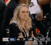 a woman sits in the stands watching a basketball game between the dallas and lva teams
