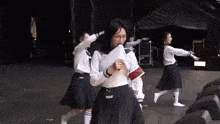 a group of girls in school uniforms are performing on a stage .