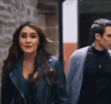 a man and a woman are walking down the street . the woman is wearing a leather jacket .