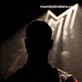 a silhouette of a man stands in front of a mumbaiindians logo