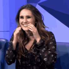 a woman wearing a choker is smiling and covering her mouth with her hands
