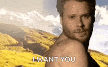 a man without a shirt is standing in front of a mountain and saying i want you .