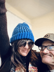 a man and a woman are posing for a picture while the woman is wearing a blue hat