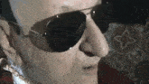 a close up of a man wearing sunglasses and a gold chain around his neck