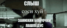 a man in a purple jacket is standing in front of a sign that says ' coci хуй ' on it .