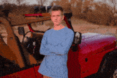 a man stands in front of a red jeep