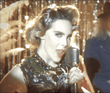 a woman singing into a microphone with a man playing a guitar in the background