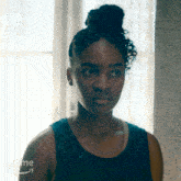 a woman in a blue tank top is standing in front of a window and the word prime is on the bottom right