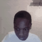 a young man in a white shirt is making a funny face while looking at the camera .