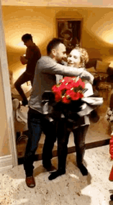 a man is carrying a woman in his arms while holding a bouquet of flowers .