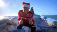 a man in a santa hat is giving a thumbs up on a boat .