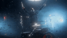 a man is playing drums in a dark room with confetti falling around him