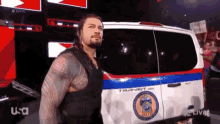 a man in a black vest is standing in front of a transit van .