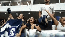 a group of people are standing in a stadium holding a flag with a shield on it .