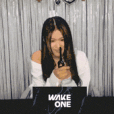 a woman is holding a pair of scissors in front of a wake one sign