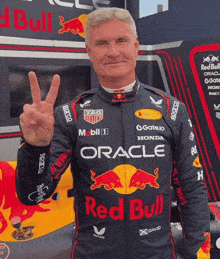 a man wearing a red bull racing suit giving the peace sign