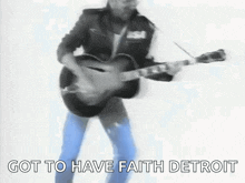 a man is playing a guitar in a black and white photo with the words got to have faith detroit below him .