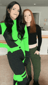 a woman in a green costume is standing next to a woman in a black crop top
