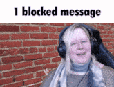 a woman wearing headphones is standing in front of a brick wall with the words 1 blocked message above her