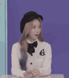 a woman wearing a black beret and a white jacket is sitting at a table .