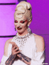 a woman with a tattoo on her arm is wearing a white dress and jewelry