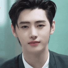 a close up of a young man 's face wearing a suit and a white shirt .