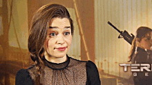 a woman making a funny face in front of a sign that says ter