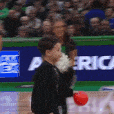 a boy is holding a red ball in front of a banner that says america