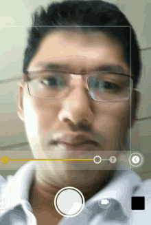 a man wearing glasses and a white shirt is being recorded