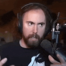a man with a beard wearing headphones and a microphone is talking into it .
