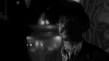 a man with a mustache and glasses is wearing a top hat and tie .