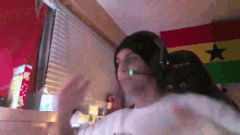 a man wearing headphones and a beanie is dancing in a room with a flag in the background .